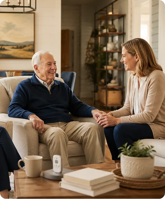 An older man with a blue pullover zip down sweater talking with his daughter while sitting in a reclining chair